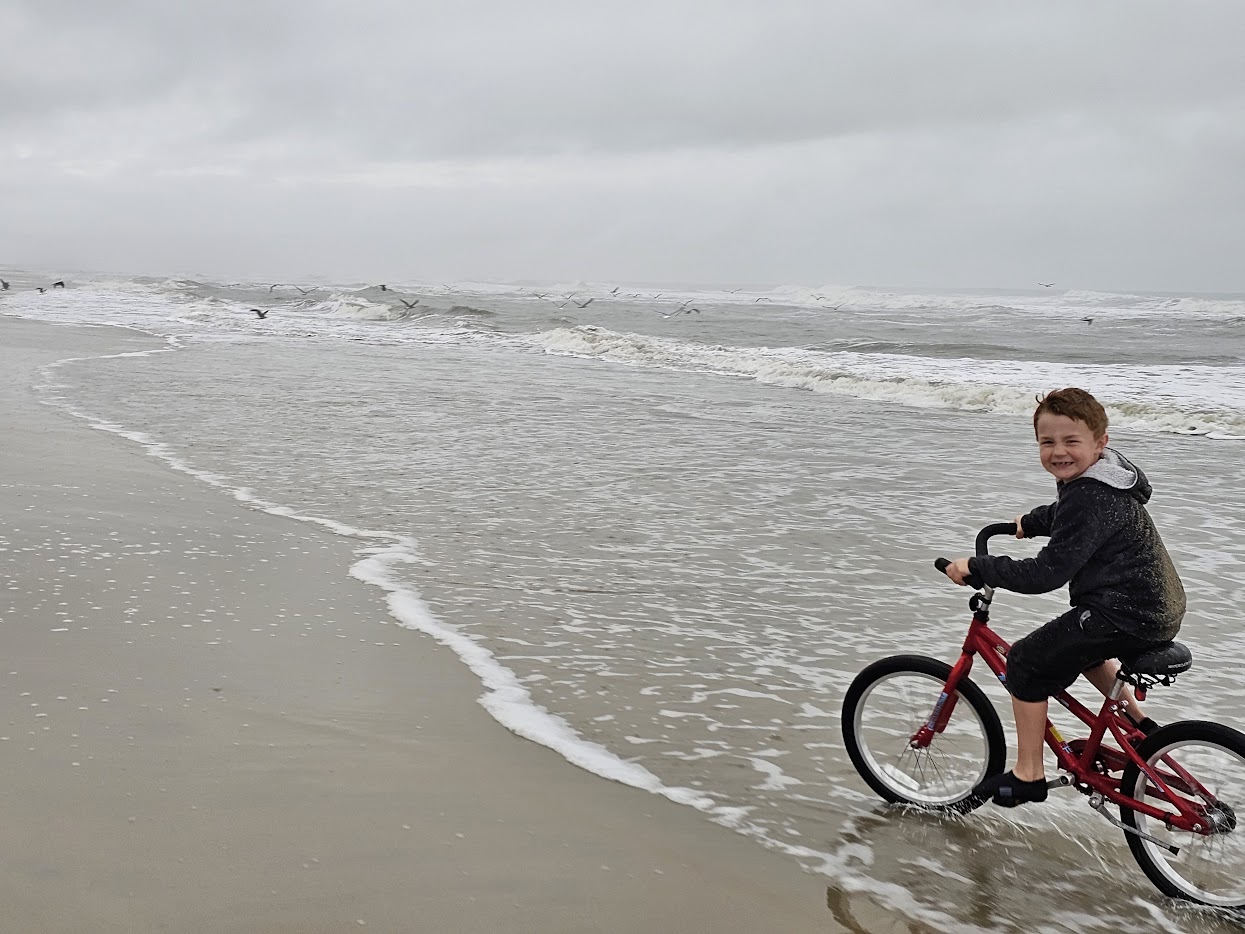 Kid biking on the beach in fall